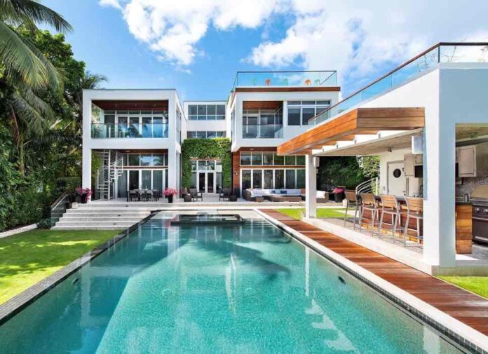 Miami home with white stucco walls, red tile roof, and palm tree in front yard.